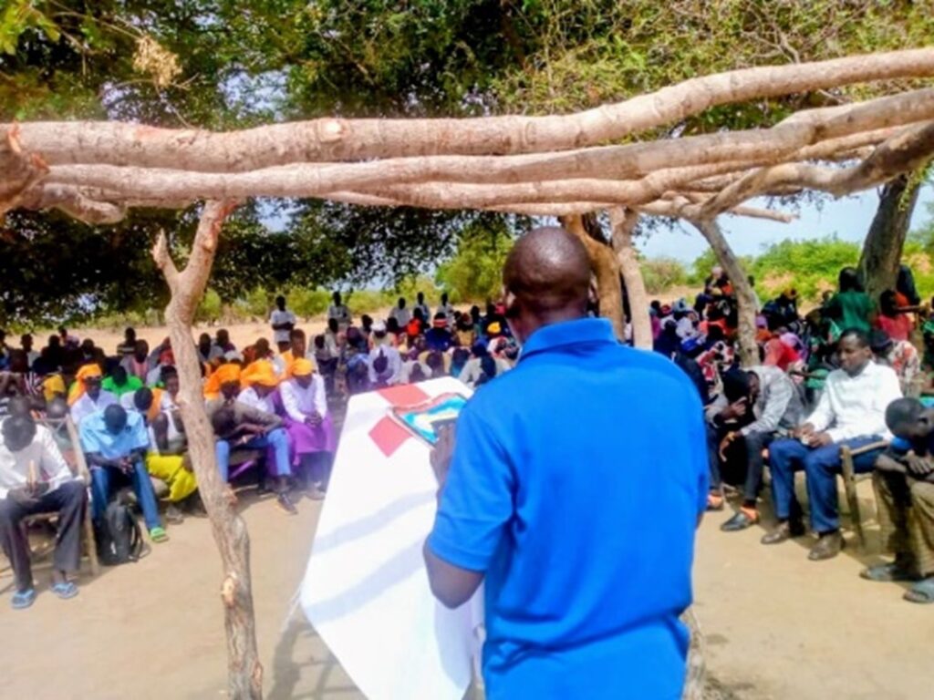 The back of a person in a blue shirt standing at the pulpit in font of the congregation 