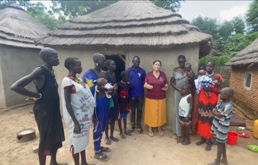 A group of people standing in front of a hut