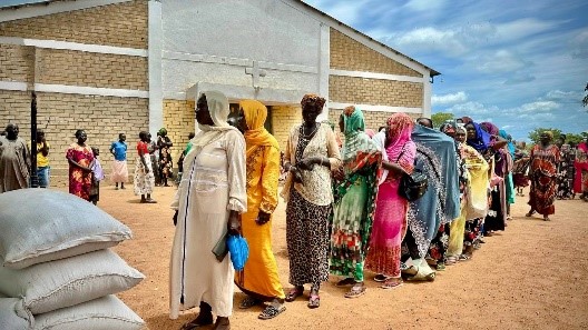 A group of people standing in a line for bags of food