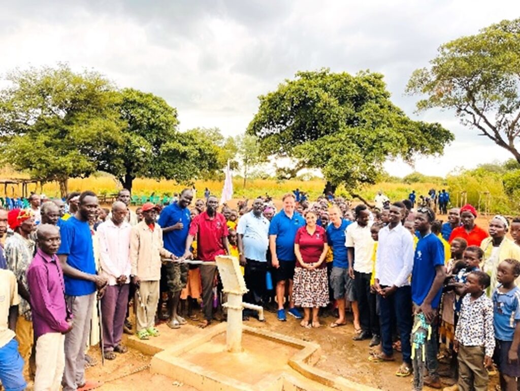 A group of people standing around a water pump