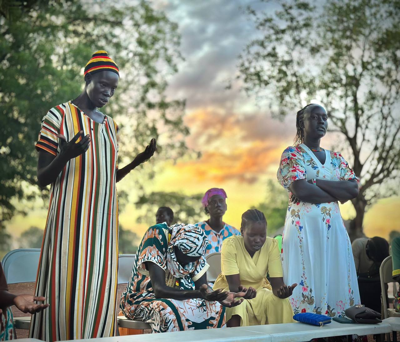 A group of people standing and sitting in prayer